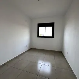 Vista interna de um corredor com paredes brancas e piso de cerâmica.