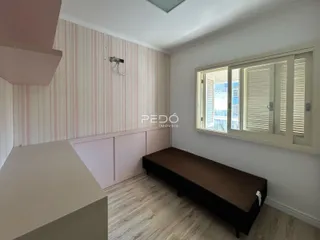 Quarto com parede listrada rosa e branca e piso de madeira clara.