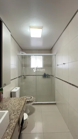 Foto de um banheiro com revestimento cerâmico e box de vidro.