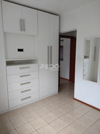 Quarto com armários brancos e piso de cerâmica em um imóvel no Brasil.