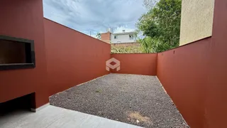 Vista externa de um pátio cercado por paredes vermelhas e com piso de cascalho.