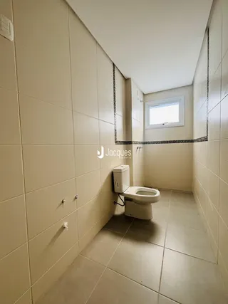 Corredor interno com revestimento de cerâmica e vaso sanitário.