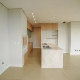 Foto interna de uma cozinha moderna com armários brancos e bancadas claras.