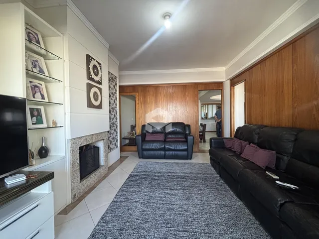 Sala de estar com sofá de couro e parede de madeira no imóvel em Lajeado.
