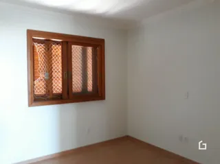 Uma parede branca com uma janela de madeira e venezianas.