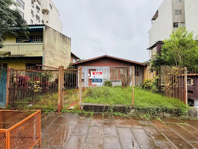 Vista externa de uma propriedade com cerca de metal e vegetação alta.