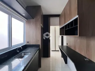 Vista da cozinha com armários de madeira e bancadas escuras.