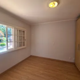 Foto interna de um cômodo com piso de madeira e janela.
