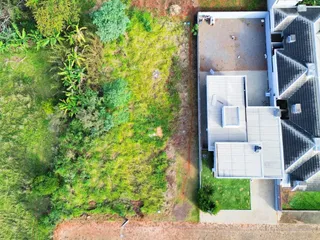 Vista aérea de uma propriedade residencial com área verde densa ao lado.
