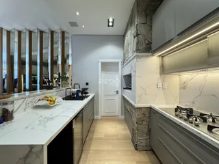 Cozinha moderna com bancadas de mármore e parede de pedra rústica.