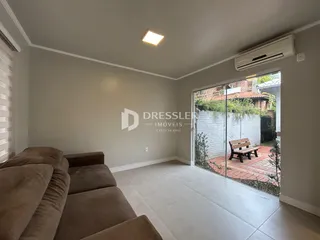 Sala de estar com sofá e porta de vidro dando para o quintal.
