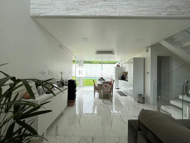 Ambiente amplo com piso claro e área de jantar integrada em um imóvel.