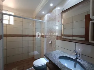 Foto de um banheiro com revestimento cerâmico e box de vidro.