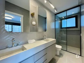 Banheiro moderno com bancada e box de vidro.