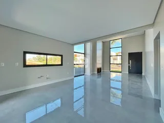 Sala de estar ampla com piso reflexivo e grandes janelas.