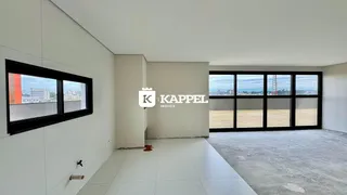Vista de um ambiente interno com grandes janelas que oferecem uma vista para um campo aberto.