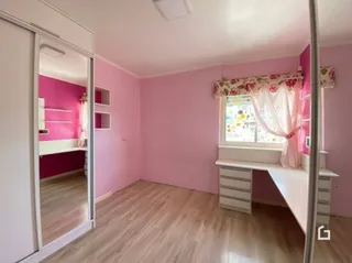 Vista interna de um ambiente com paredes rosa e piso de madeira clara.