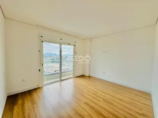 Sala de estar com piso de madeira clara e portas de vidro que dão para a vista.