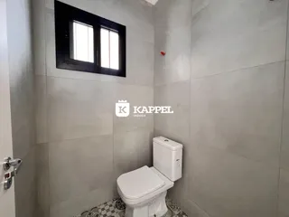 Foto de um banheiro com paredes claras e uma janela escura.