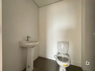 Foto de um banheiro com pia e vaso sanitário em paredes brancas.
