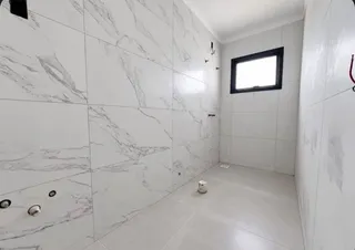 Corredor com revestimento de azulejos brancos com veios de mármore.