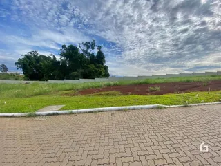 Vista externa de uma propriedade com gramado e área de terra.