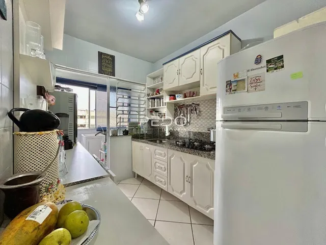 A cozinha apresenta armários brancos e bancadas claras.