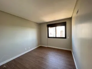 Sala de estar com piso de madeira e janela mostrando a vista externa.