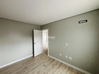 Ambiente interno de uma sala com paredes cinzas e piso de madeira clara.