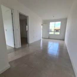Hall de entrada com piso claro e paredes brancas.