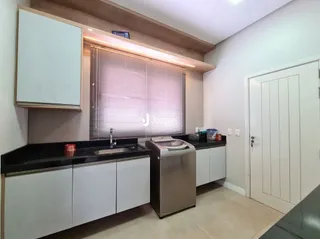 Foto de uma cozinha interna com armários brancos e bancadas escuras.