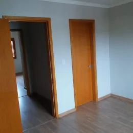 Vista de um corredor interno com portas de madeira em uma residência.