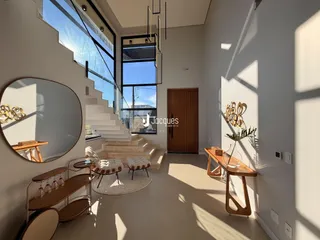 Sala de estar com escadaria e grandes janelas.