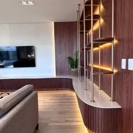 Sala de estar com piso de madeira e parede revestida em painéis escuros.
