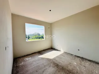 Vista interna de um cômodo com piso de concreto e janela.