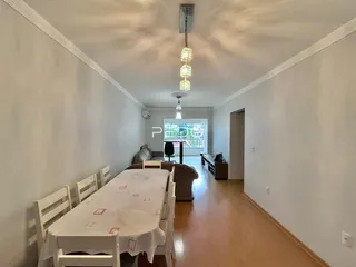 Ambiente interno de uma sala de jantar longa com piso de madeira.