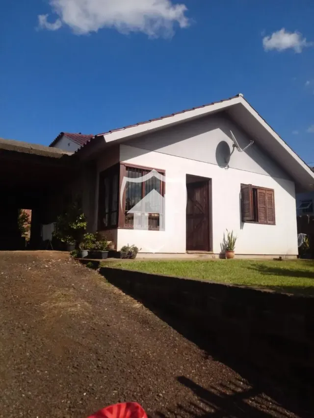 Fachada de uma casa em Lajeado, Brasil, com telhado inclinado e paredes brancas.