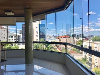 Vista panorâmica da cidade de Lajeado observada a partir de uma varanda com guarda-corpo de vidro.