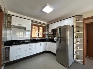 Cozinha com armários brancos e bancadas escuras em um imóvel no Brasil.