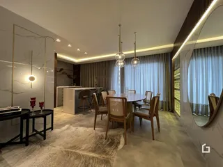 Ambiente interno de sala de jantar com grandes janelas e cortinas.
