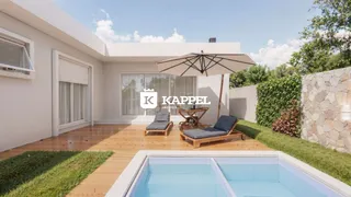 Foto da área externa com piscina e deck de madeira em uma residência.