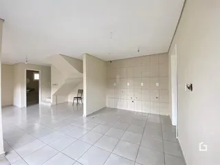 Espaço interno amplo com piso de cerâmica e paredes brancas.
