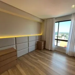 Quarto com piso de madeira e iluminação embutida na parede.