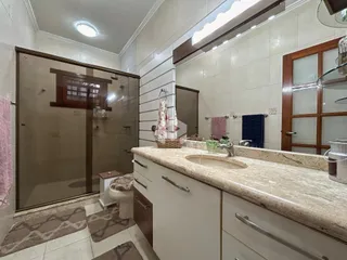 Banheiro com bancada de mármore e box de vidro.