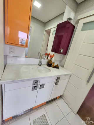 Visão de uma bancada de cozinha com armários brancos e piso de cerâmica clara.