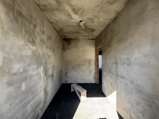 Corredor com paredes de reboco e piso escuro.