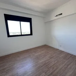 Vista interna de um cômodo com piso de madeira e janela.