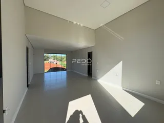 Ambiente interno de uma sala ampla com piso claro e porta de vidro.
