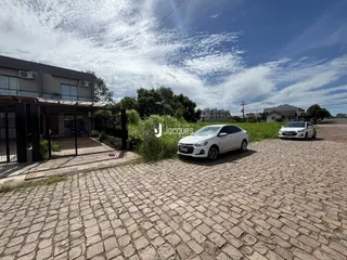 Vista externa de uma propriedade com entrada pavimentada e cerca.
