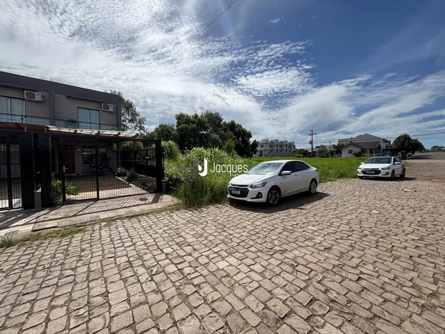 Vista externa de uma propriedade com entrada pavimentada e cerca.